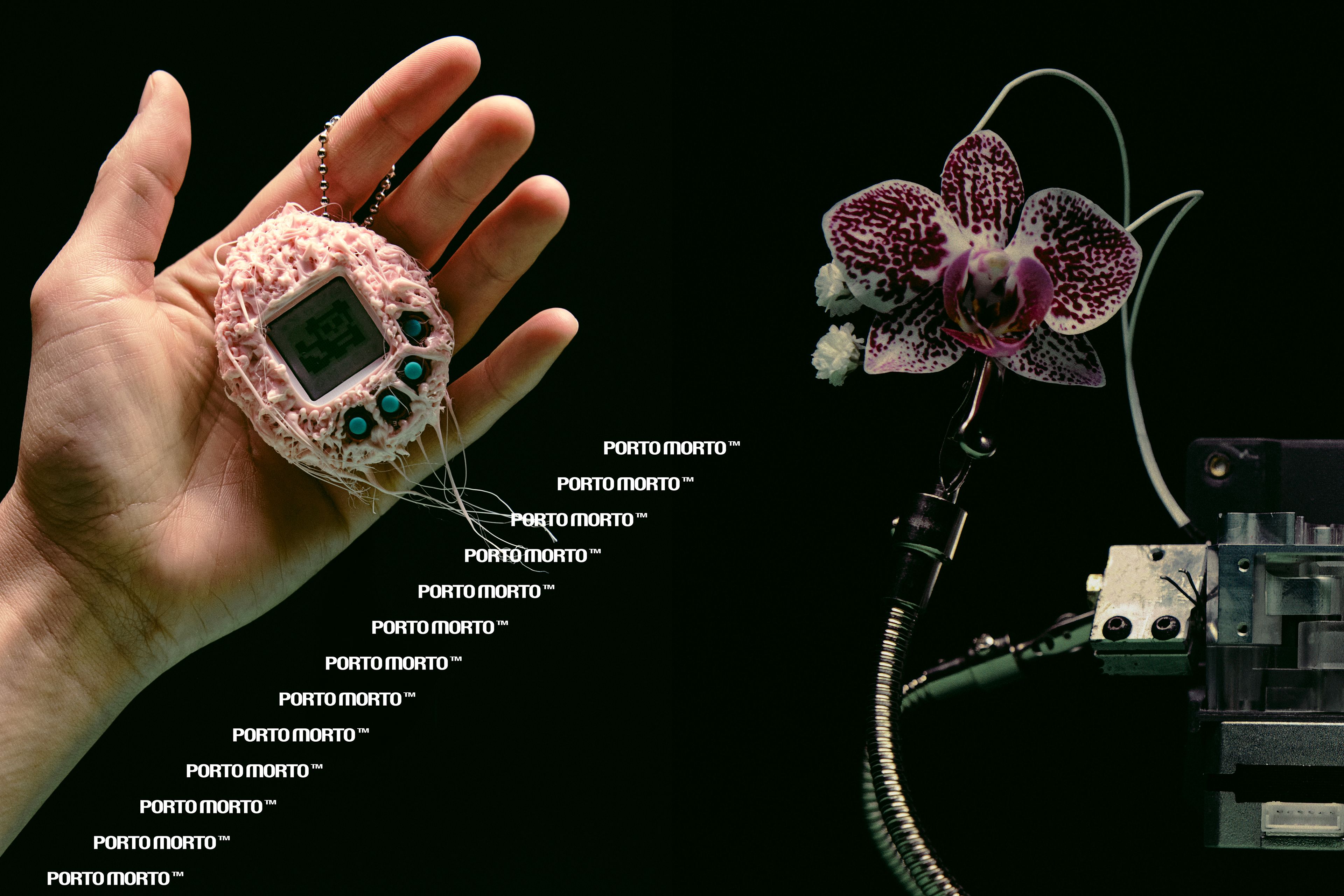 A hand holding a knitted pink gadget charm beside an orchid