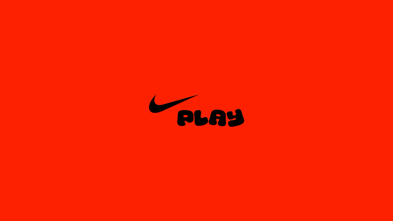 Nike Play logo, a black swoosh above rounded PLAY lettering, on a red-orange field