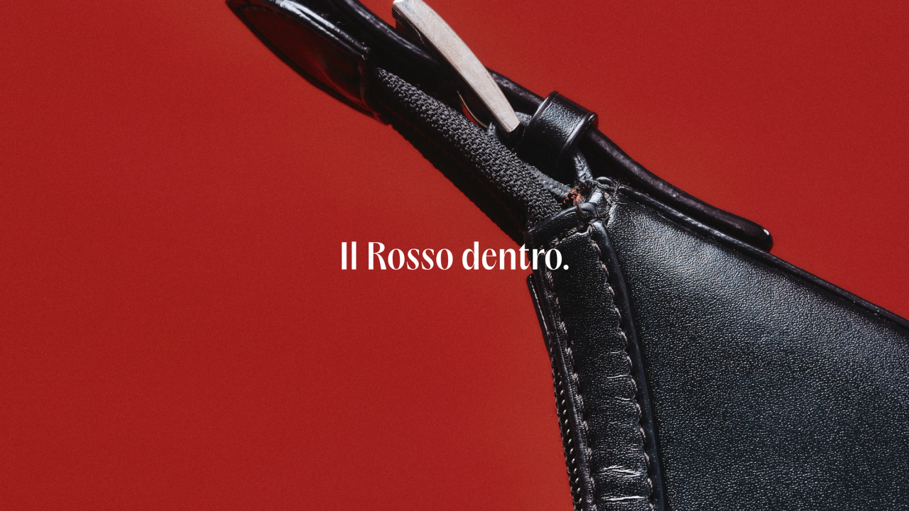 A zipped black leather bag on red beside the words Il Rosso dentro