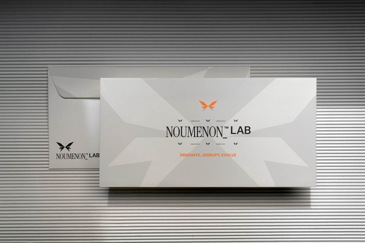 Two grey NOUMENON LAB envelopes, one reading "Innovate, disrupt, evolve", against a ribbed wall