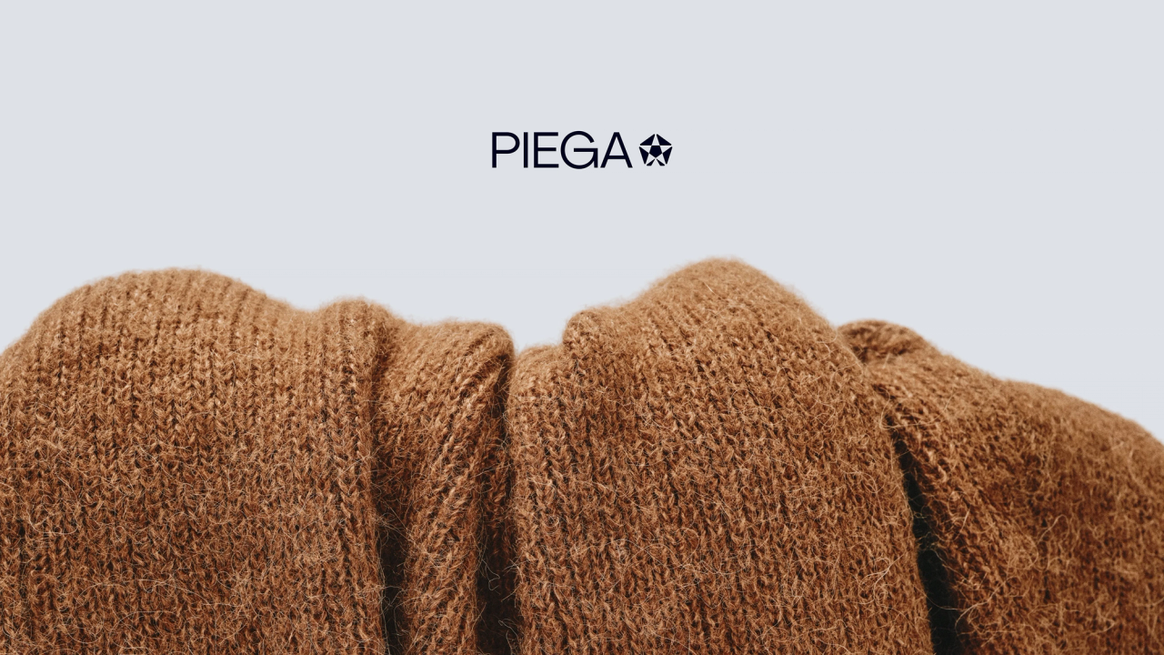 Bunched brown knitwear below the PIEGA wordmark on pale grey