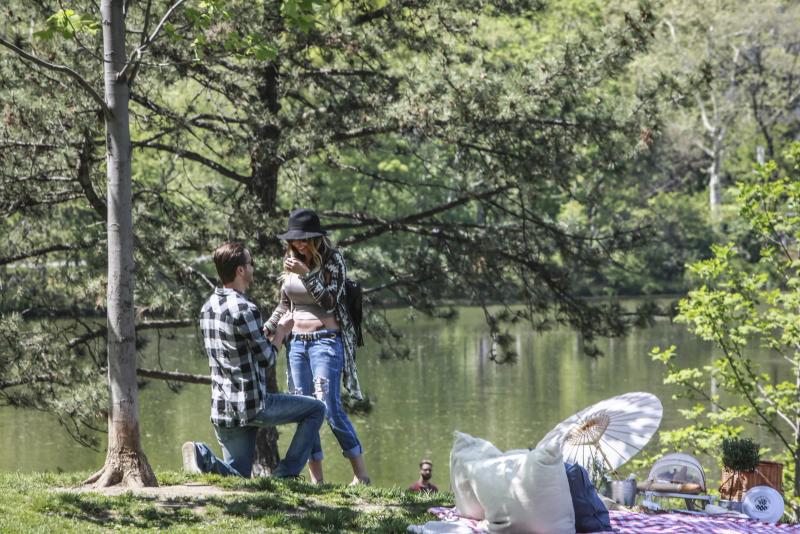 Chris proposing to Jenna beside a lake, a picnic set up nearby