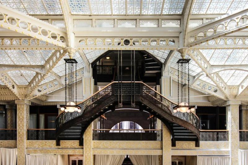 Interior view of the Rookery Building Light Court in Chicago, featuring ornate iron staircases, glass ceilings, and intricate architectural details flooded with natural light.