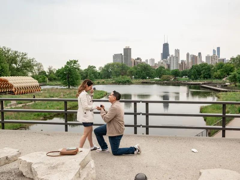 Surprise proposal photographed by Lincoln Park lagoon with the Chicago skyline