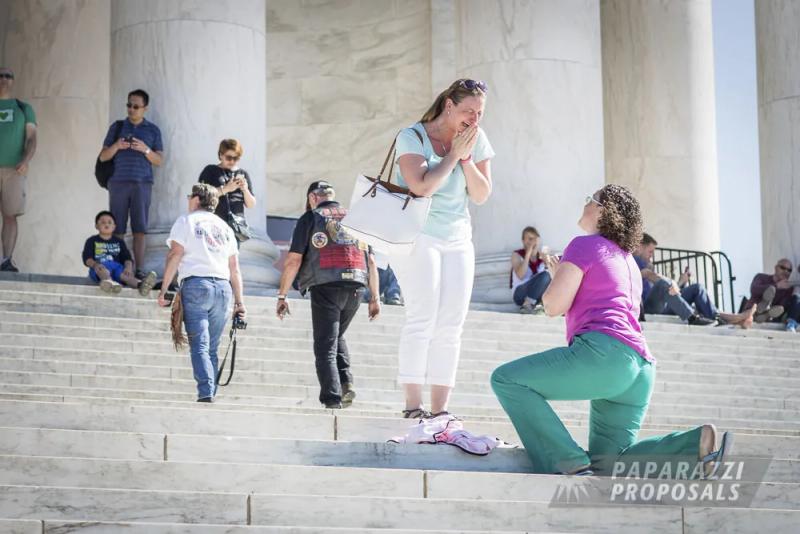 Amy on one knee proposing to Julie on a monument staircase