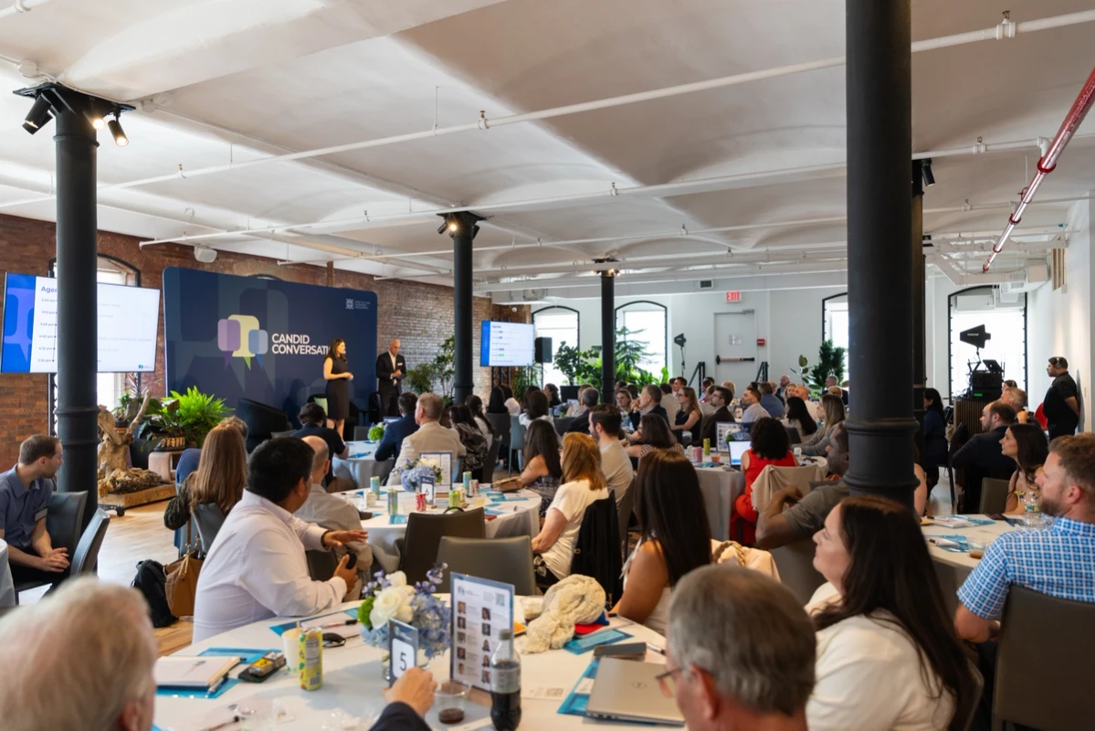 Attendees seated at tables during a Candid Conversations session.