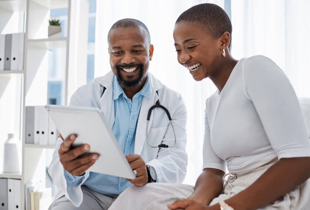 Doctor, healthcare and medicine with a patient talking test results and progress on a tablet in a hospital clinic. Trust, help and medical consulting with a professional medicare worker in his office.