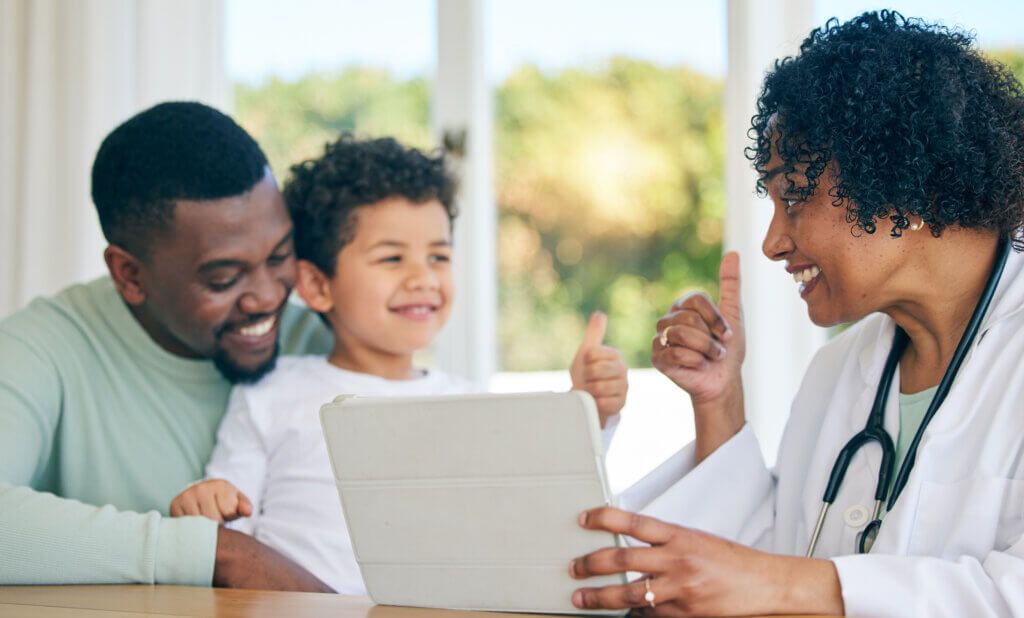 Pediatrician, father and child with thumbs up from patient edication on a tablet with good news. Happy kid, dad and doctor in a clinic consultation office with a healthcare worker and smile in hospital.