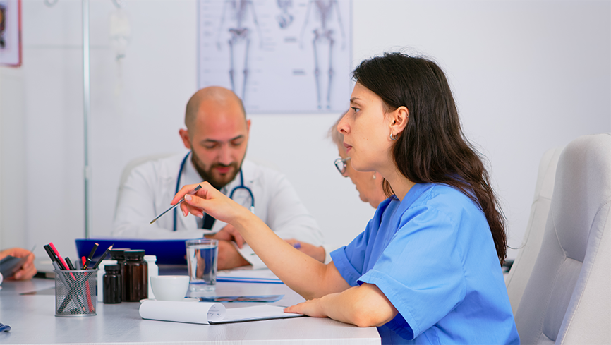 Healthcare providers discussing cases around a table in a back office