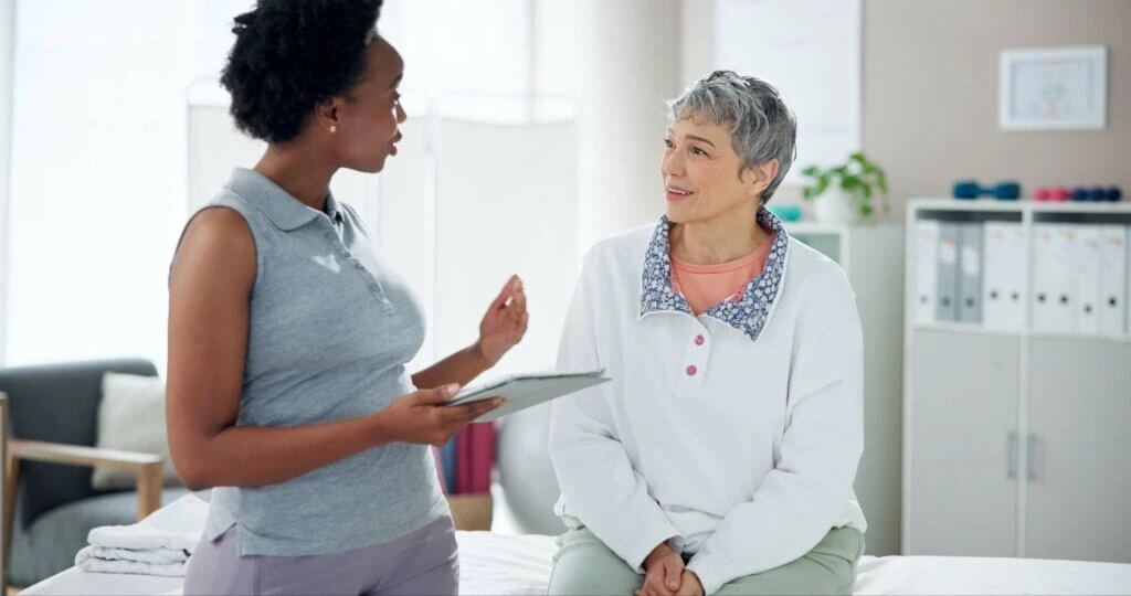 Women, doctor with POC tablet with patient for consultation, medical help or healthcare at clinic. Female person, orthopedic and senior client with technology for explanation at private practice.