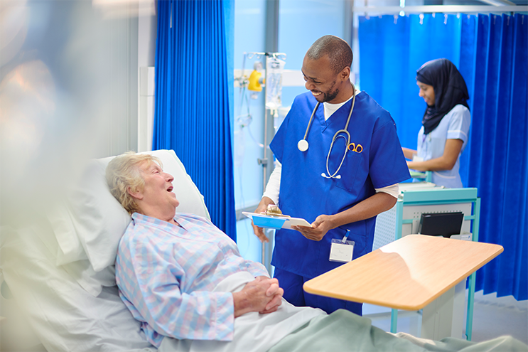 Nurse talking with a smiling patient in a hospital bed