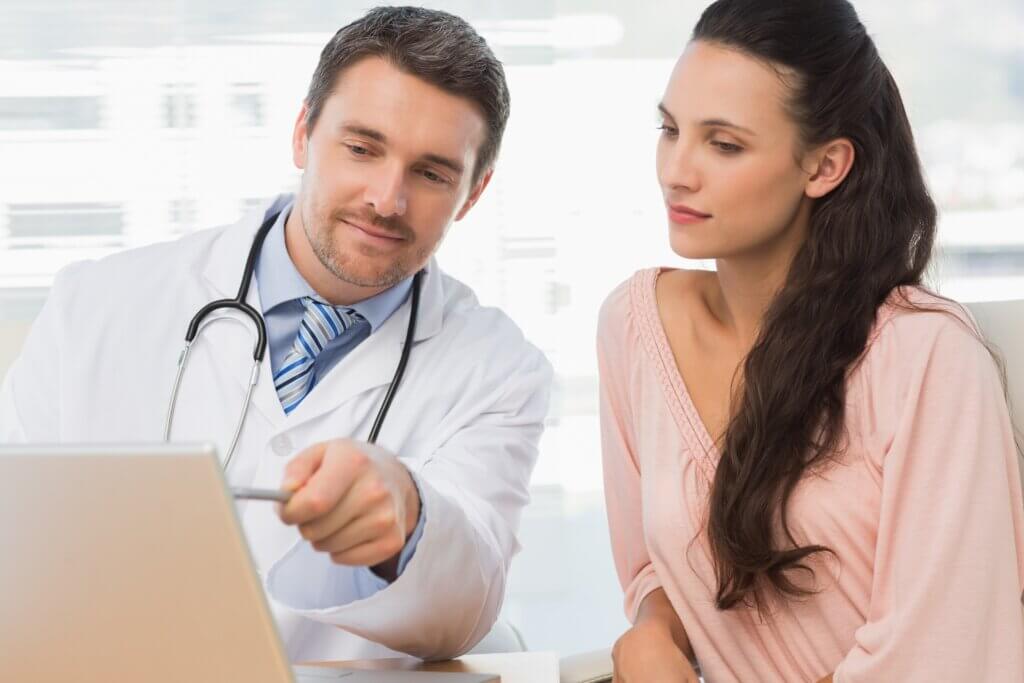 Male doctor showing something on laptop to patient