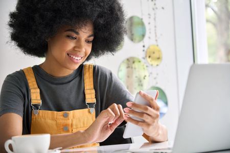 Young Gen Z hipster woman having coffee on the phone