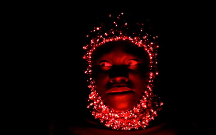 gezicht in rood licht en helm van belletjes