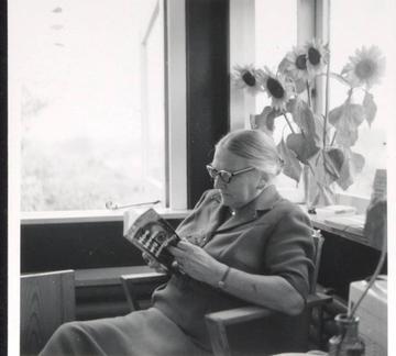 Zwart-witfoto van Truus Schröder, lezend in een stoel in het Rietveld Schröderhuis