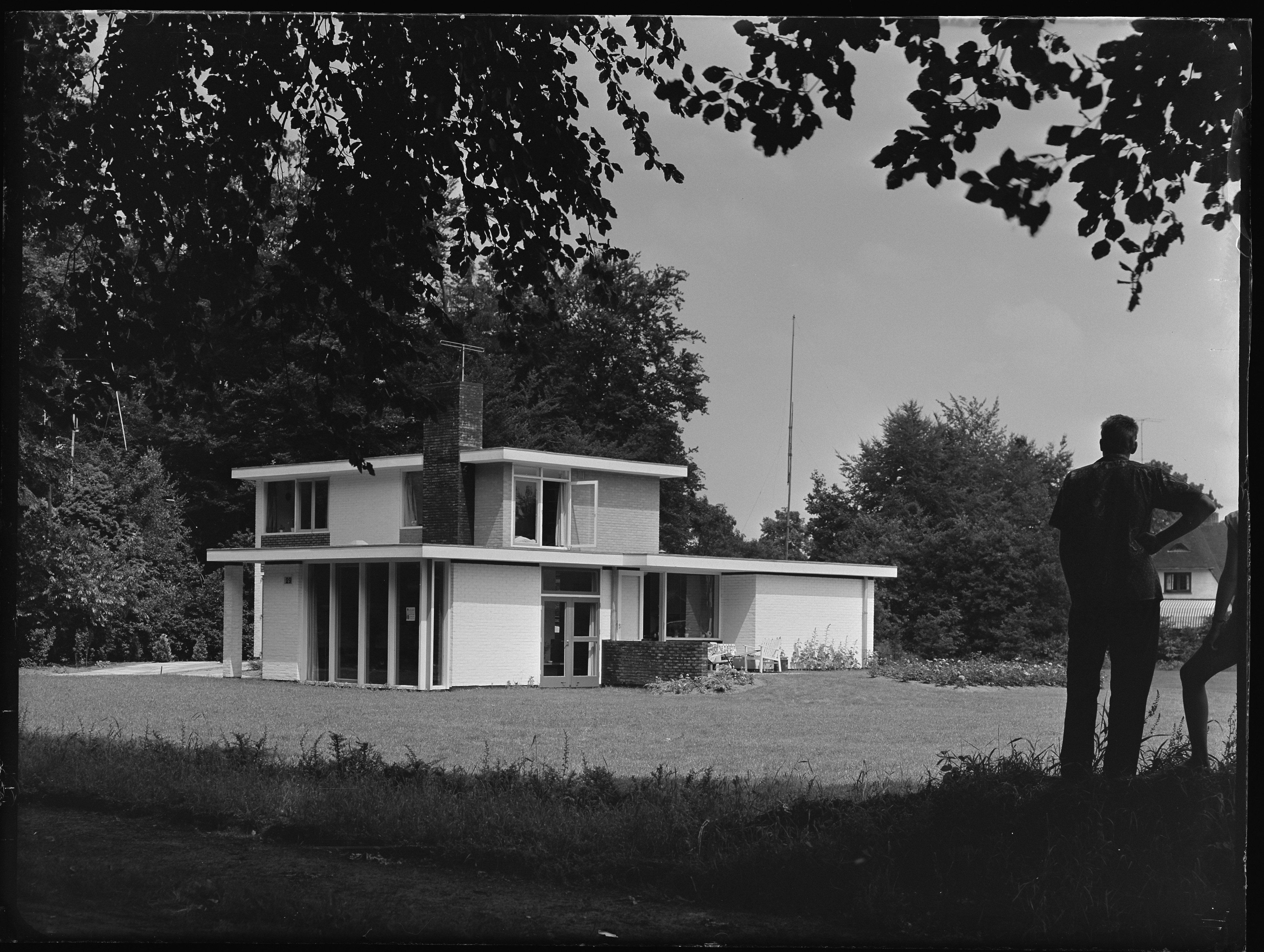 Detached two-storey house with a flat roof. White façades. 