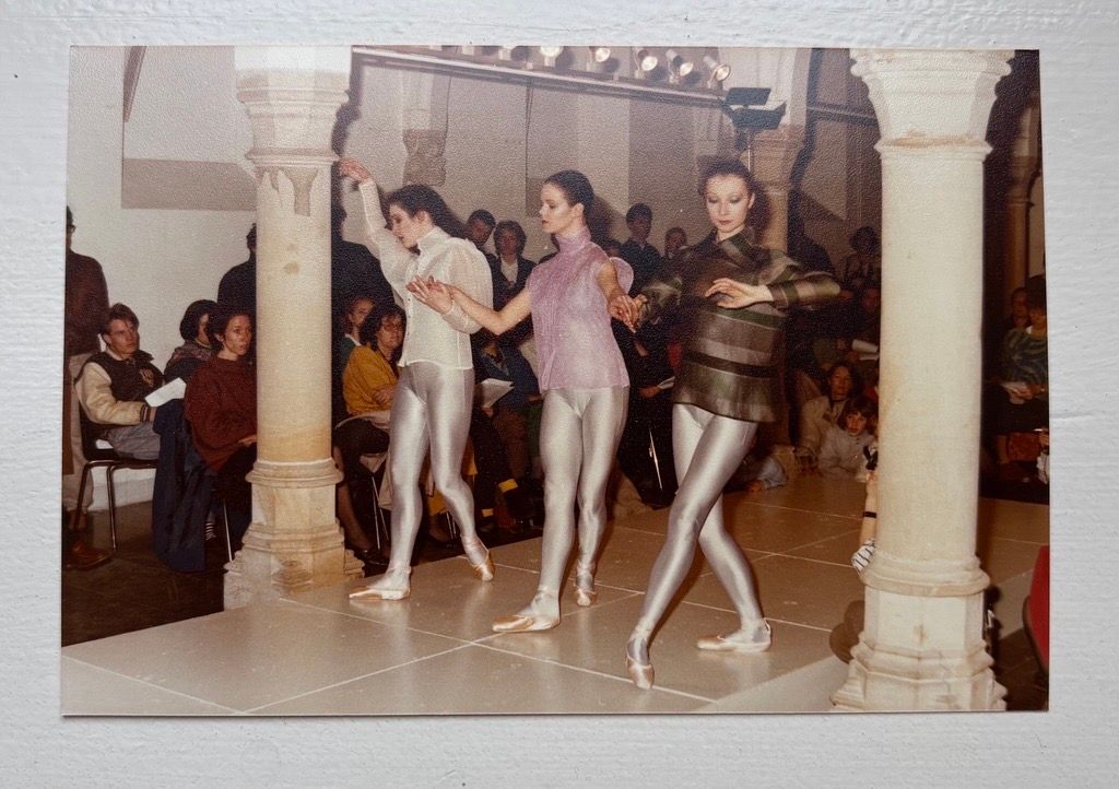 Drie mensen doen balletpassen op een podium, publiek kijkt toe