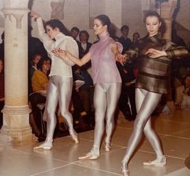 Drie mensen doen balletpassen op een podium, publiek kijkt toe