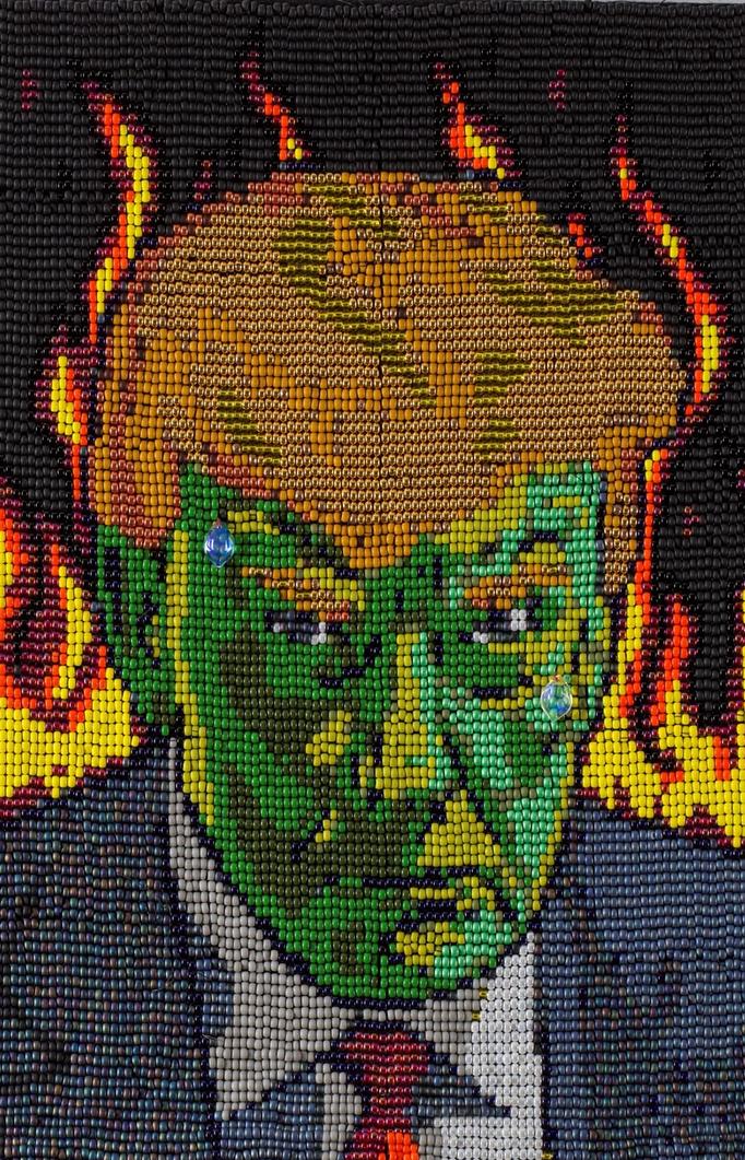 Een geborduurd portret van Donald Trump met een groen gezicht, omringd door vlammen.