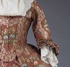 De ingesnoerde taille van een bruine damesjapon met bloemen.