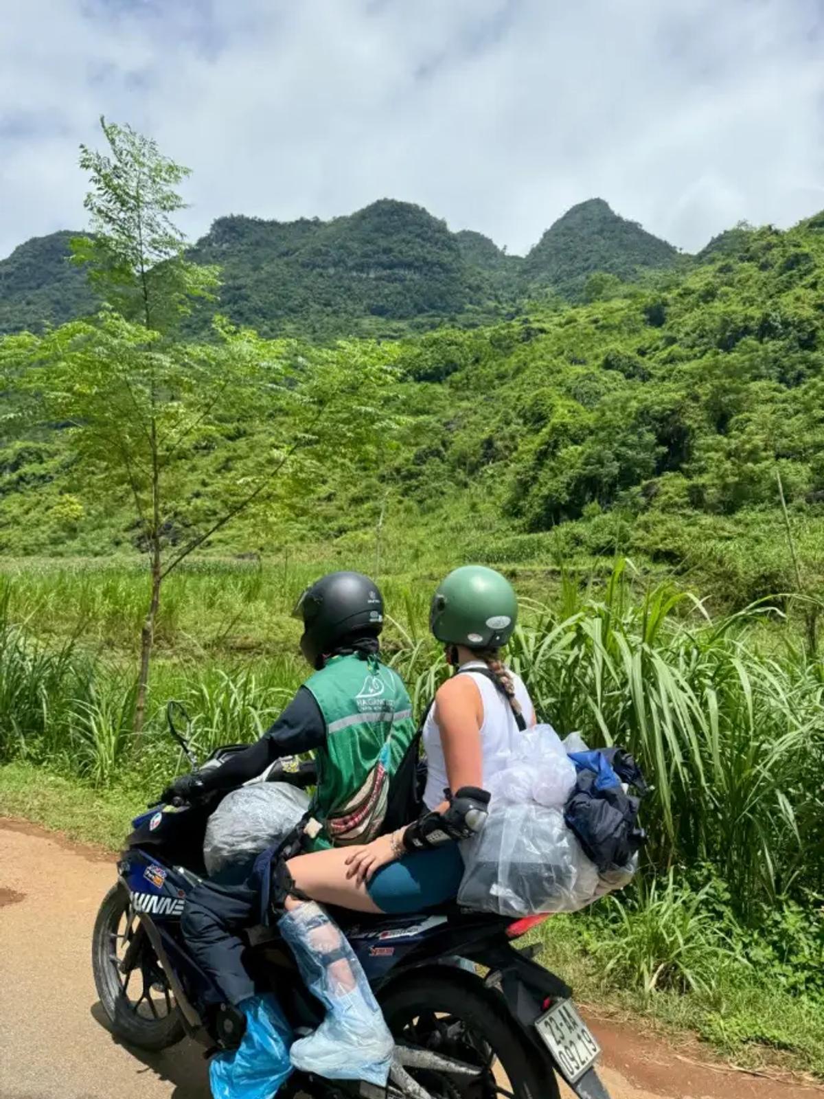Two travelers on a motorbike looking out over the green mountains of Ha Giang, Vietnam