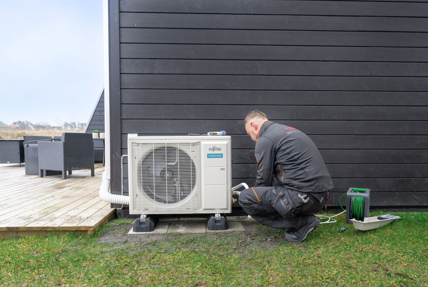 Varmepumpe montør fra Fujitsu jobber med å montere utedelen til varmepumpen.