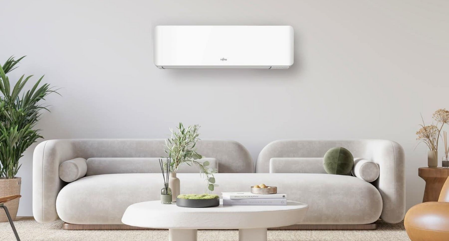 Varmepumpe på veggen i stua over sofaen i ei moderne, nordisk stue. Gir både lavere strømregning og mer behagelig inneklima. Kan kjøpes på nedbetaling.