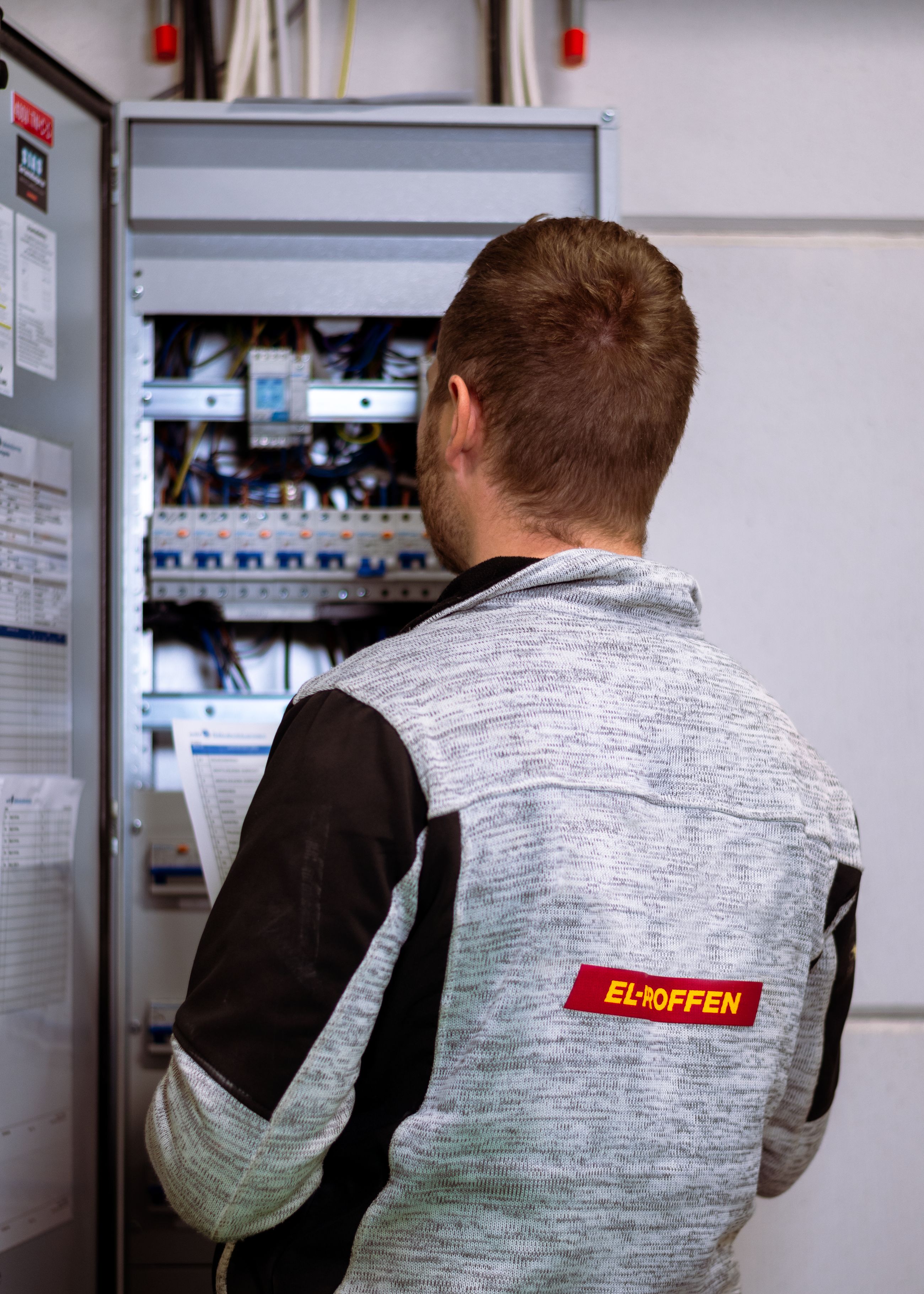 Elektriker holder en kursoversikt foran sikringsskap under elkontroll av bolig