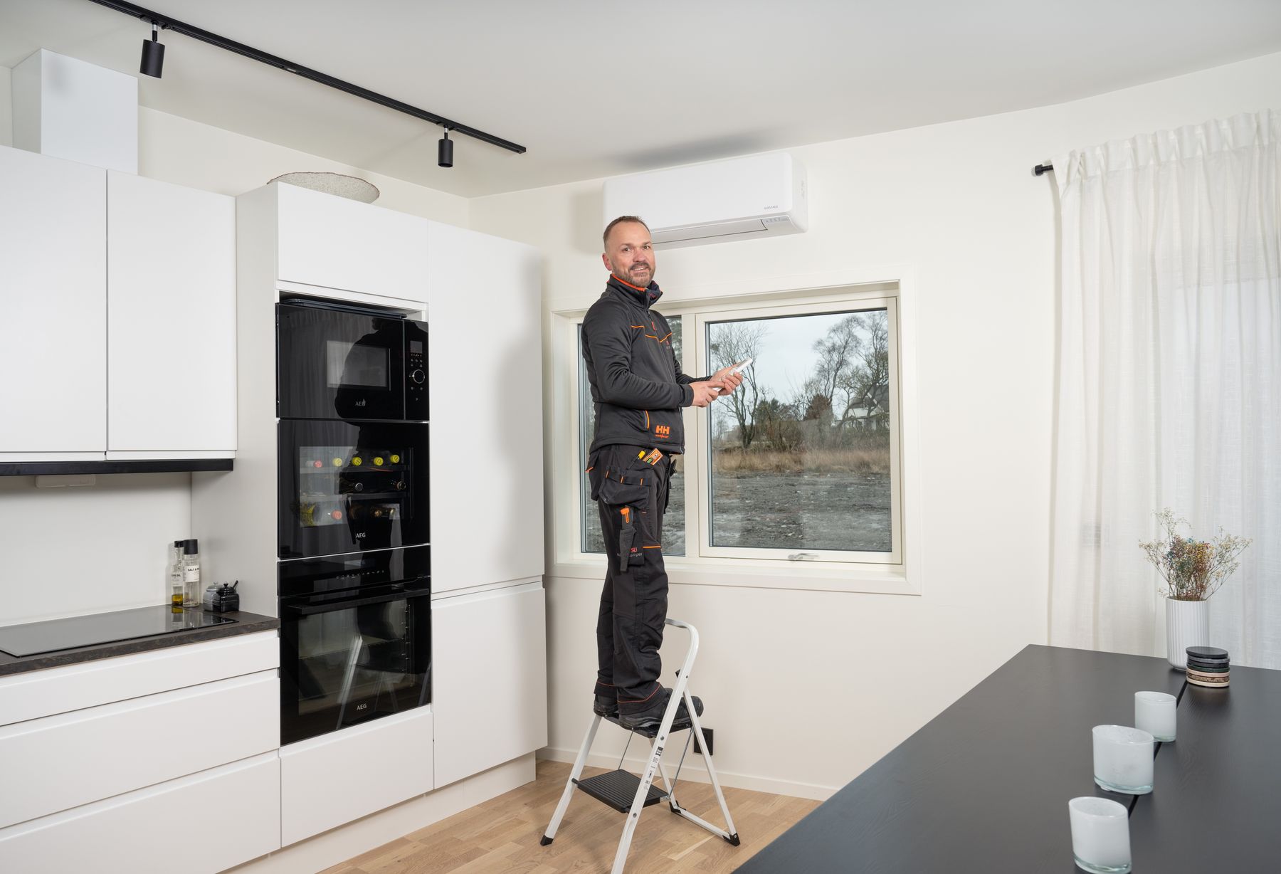 Varmepumpe montør står på en stige og er nettopp ferdig med å montere innedelen til en Fujitsu varmepumpe.