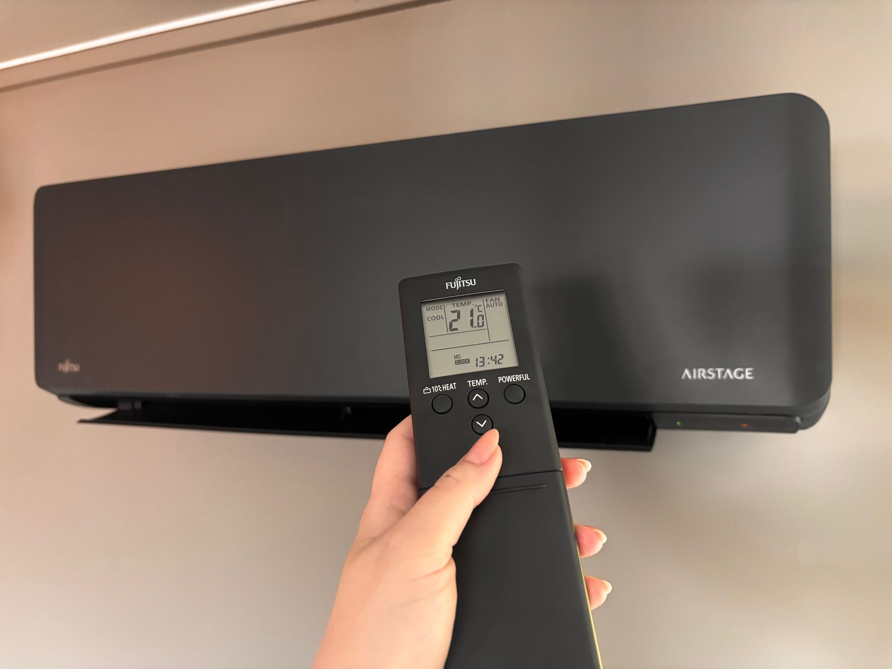 Fjernkontroll som peker på en varmepumpe innedel og endrer modus til kjøling.