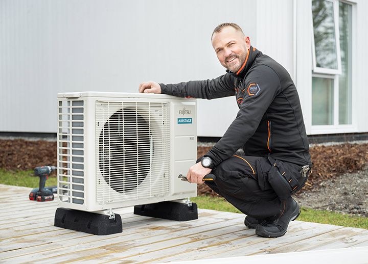 En montør sammen med utedelen til en varmepumpe.