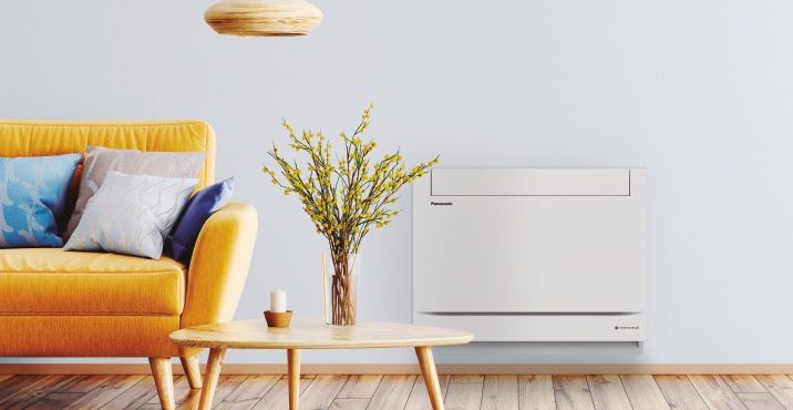 Den diskré varmepumpen Panasonic Z25 gulvmodell, ferdigmontert i ei nordisk stue med en sprek gul sofa.