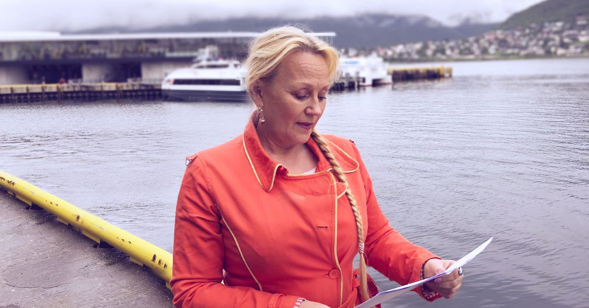 Kvinne står på ei kai og leser et papirark