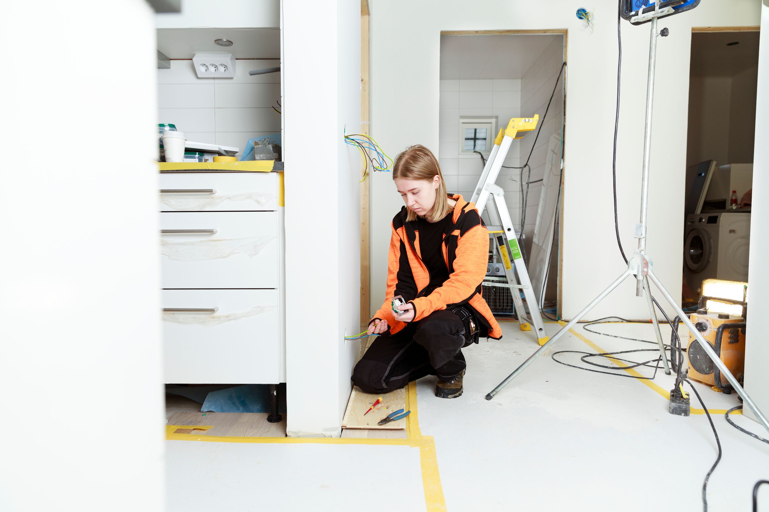 Elektriker bruker skrutrekker for å montere lys eller elektrisk utstyr under renovering av bad eller vaskerom.