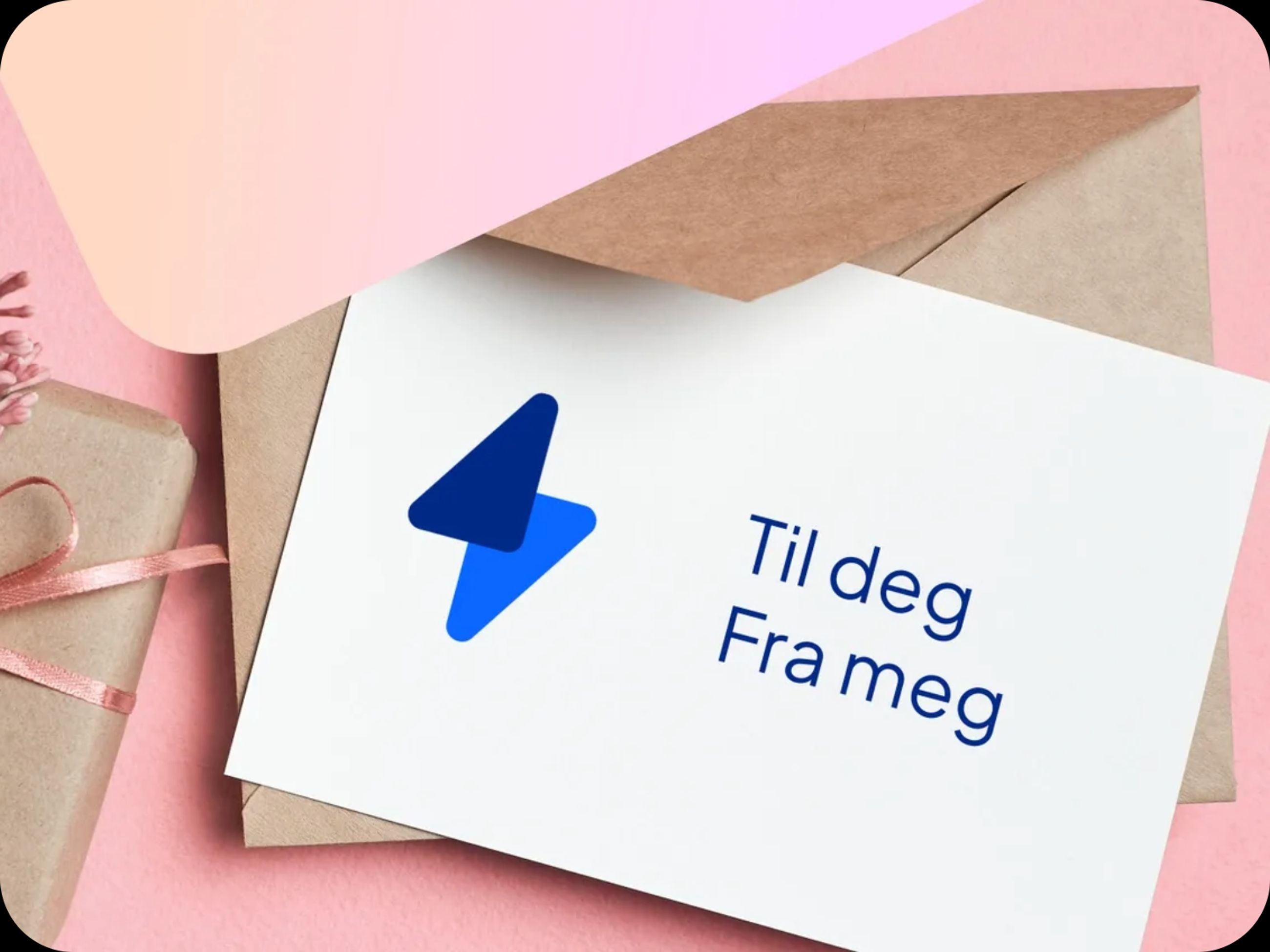 Eg gavekort på strøm med teksten til deg fra meg. Kortet ligger oppå en konvolutt, og ved siden av ligger det en pakke i gråpapir med rosa silkebånd. Bakgrunnen er rosa. 
