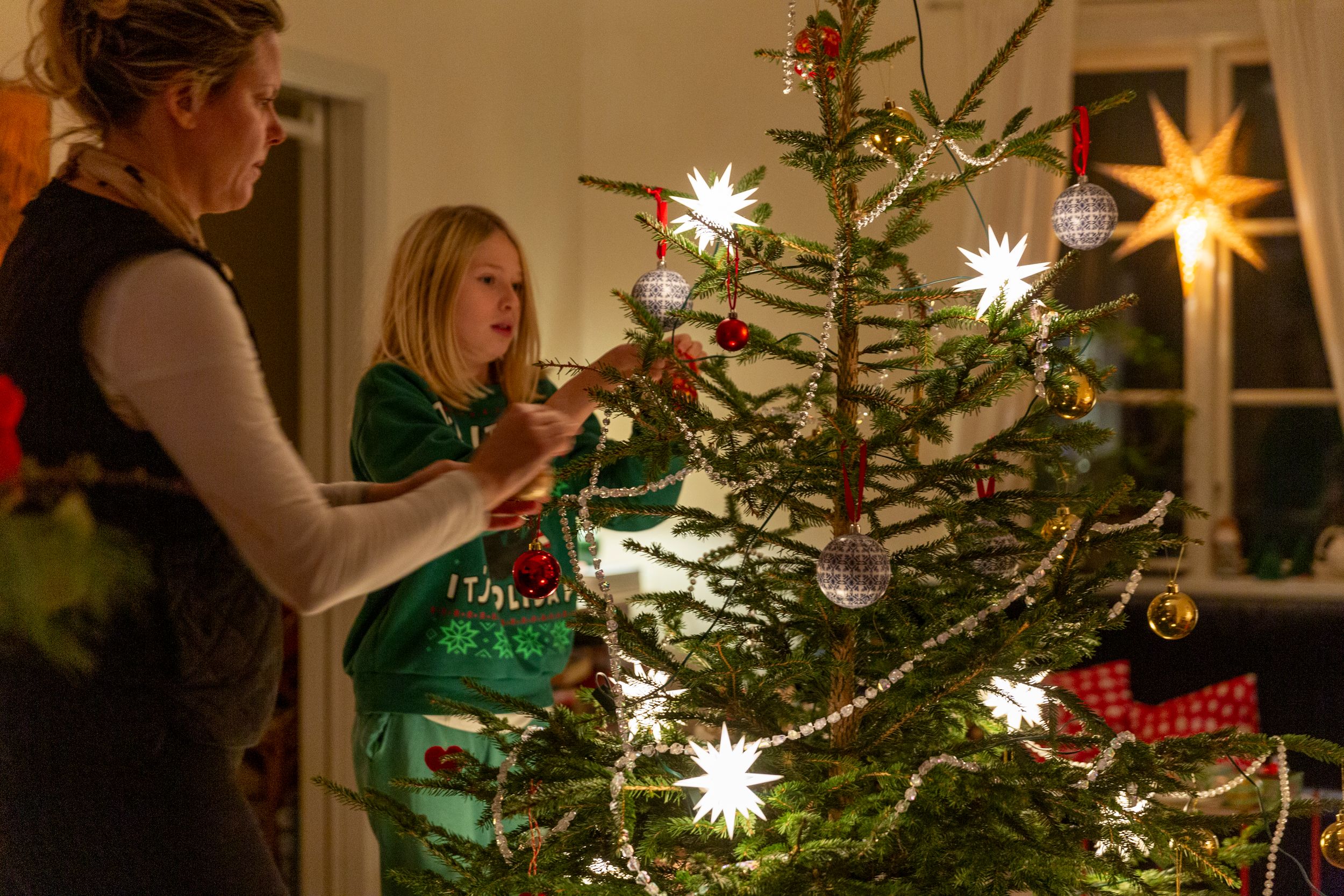 Familie som gjør siste juleforberedelser, og pynter juletreet før middagen skal lages. 