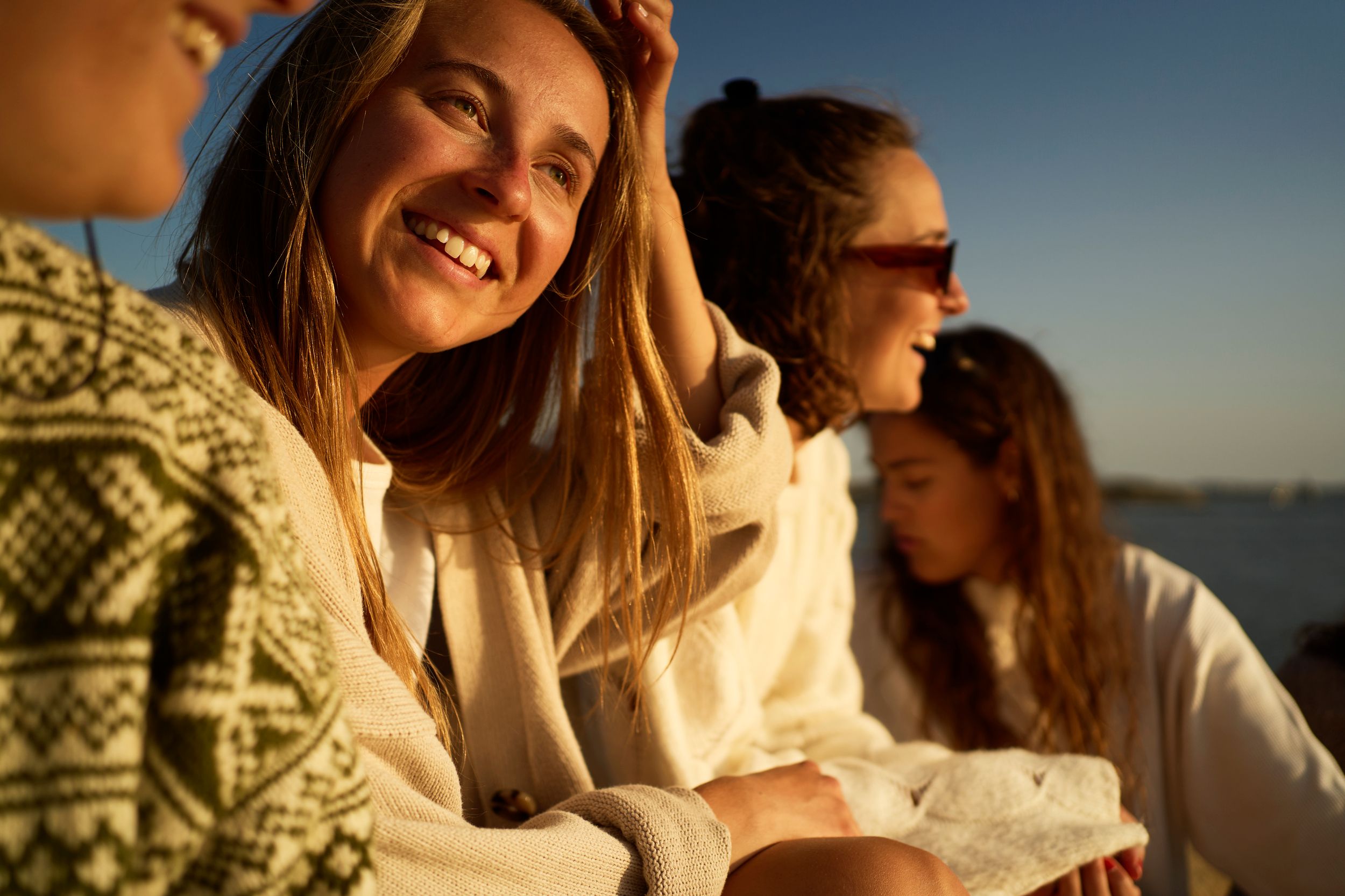 Ei dame med blondt hår ser ut av et vindu på ei ferge, med utsikt over en fjord. Hun smiler beskjedent og har et gult hårbånd på hodet.