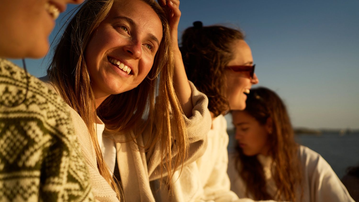 Ei dame med blondt hår ser ut av et vindu på ei ferge, med utsikt over en fjord. Hun smiler beskjedent og har et gult hårbånd på hodet.