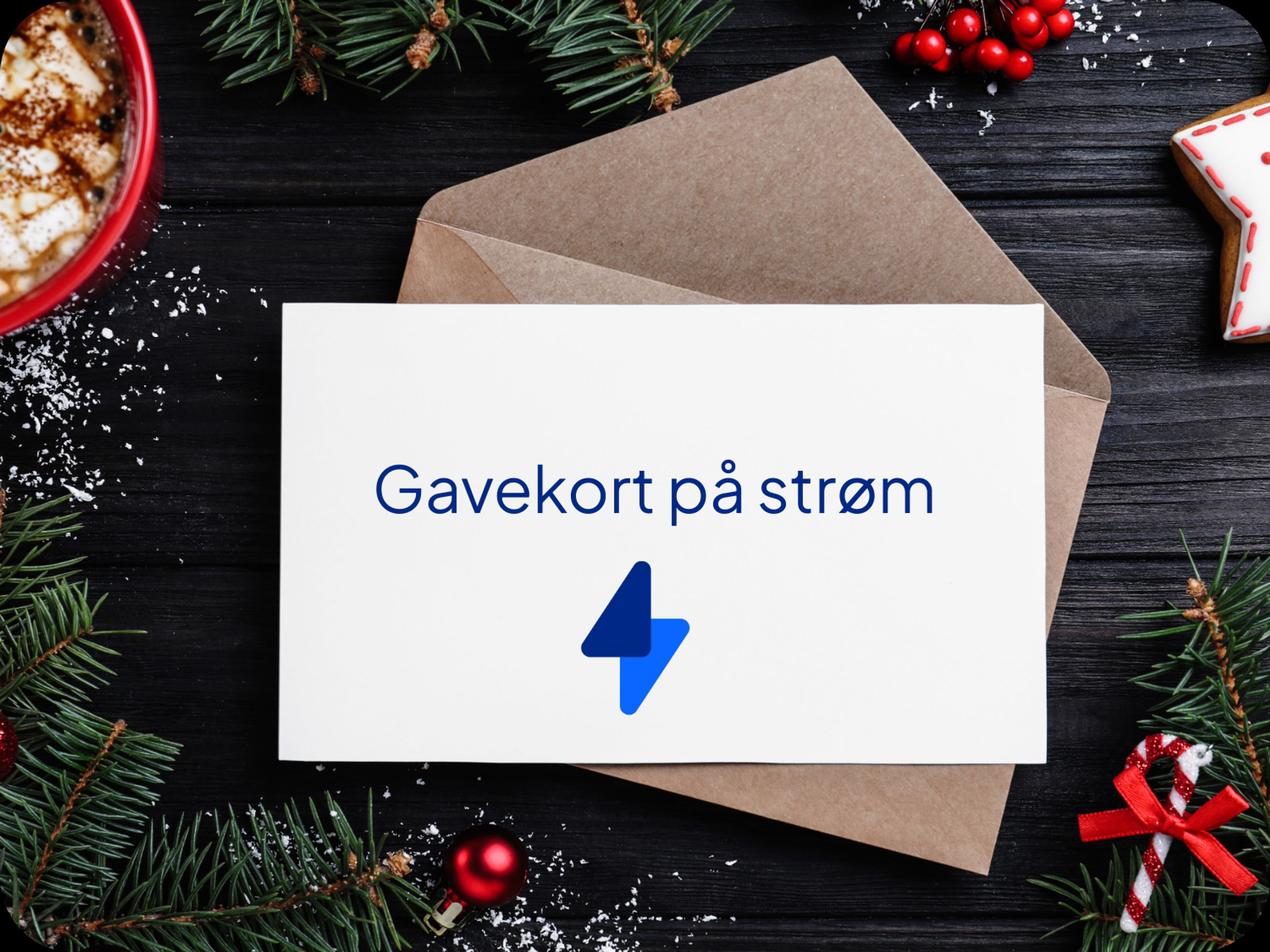 Et gavekort på et bord på en konvolutt hvor det står gavekort på strøm. I bakgrunnen ser man granbar, en kopp kakao og pepperkaker som bidrar til julestemning.