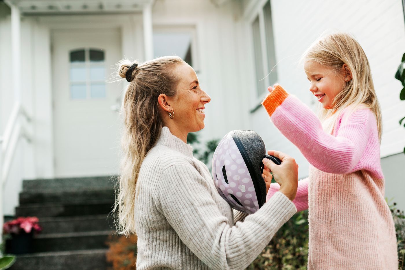 En ung familie leker sammen. Moren ser ned på barnet sitt på 2 år mens hun kiler han, og faren passer på og holder rundt dem. Et flott øyeblikk.