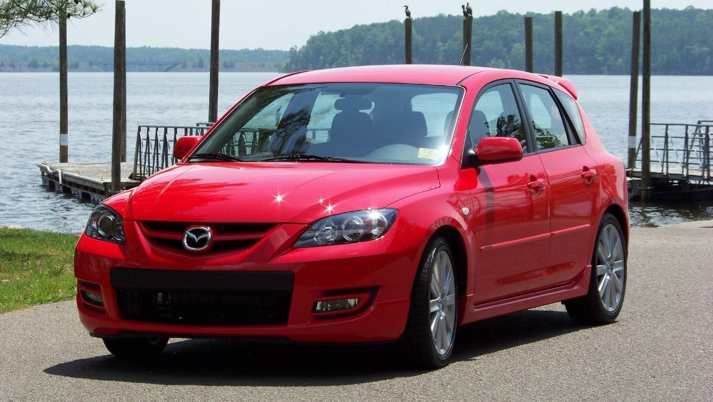 A red car parked on a road by a body of water Description automatically generated with medium confidence