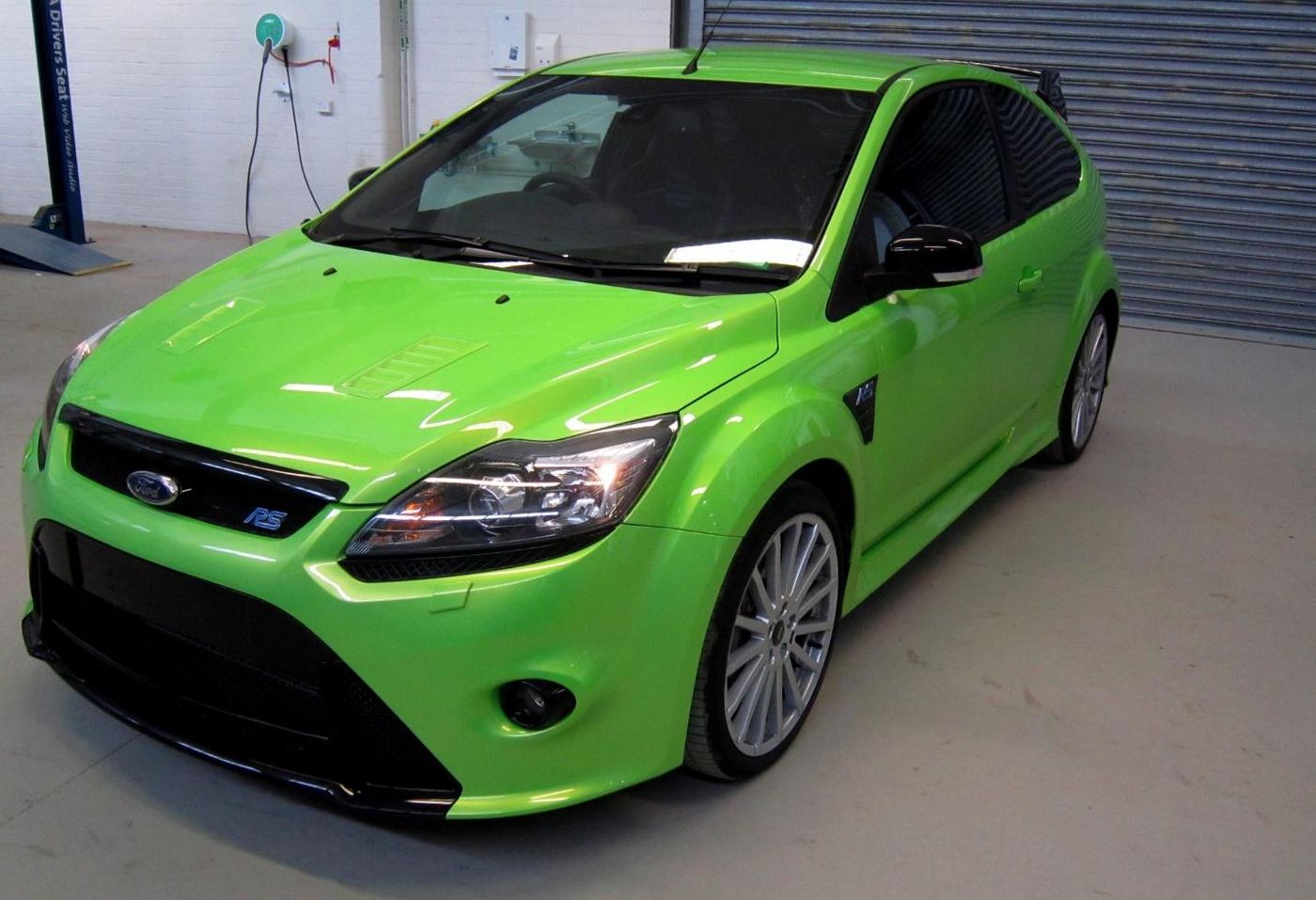 A green car parked in a garage Description automatically generated with medium confidence