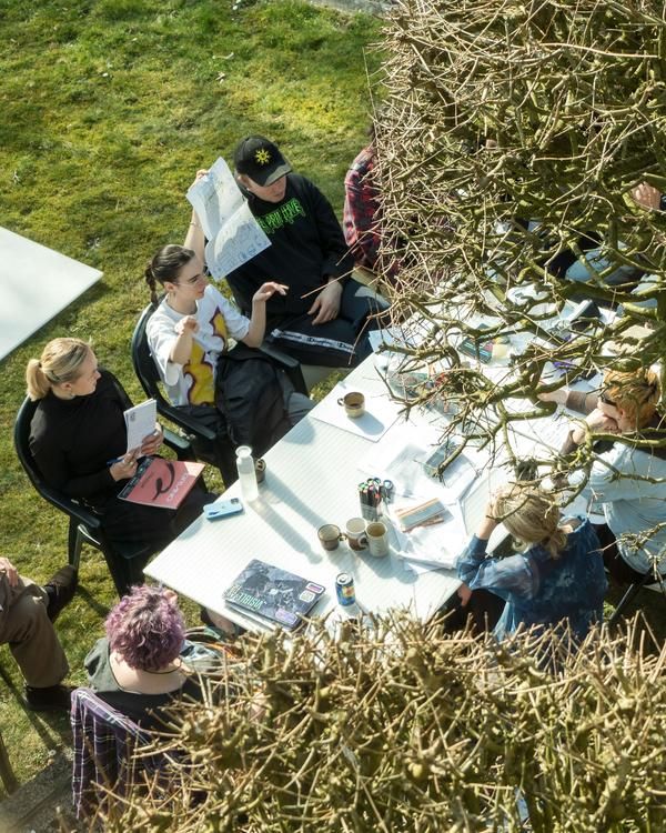 People discussing around a table outside on the grass