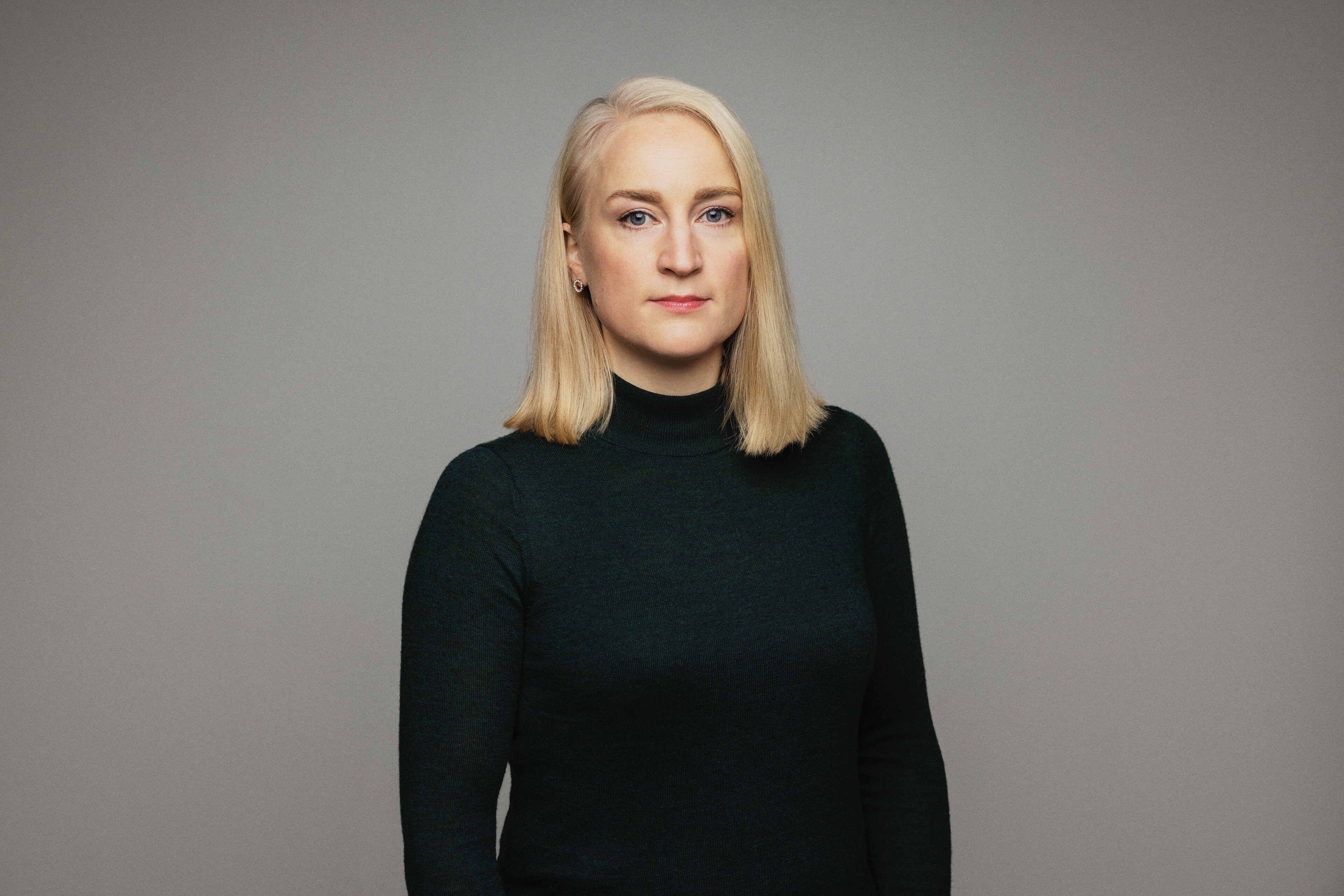 A blonde woman with straight hair open in a black polo shirt