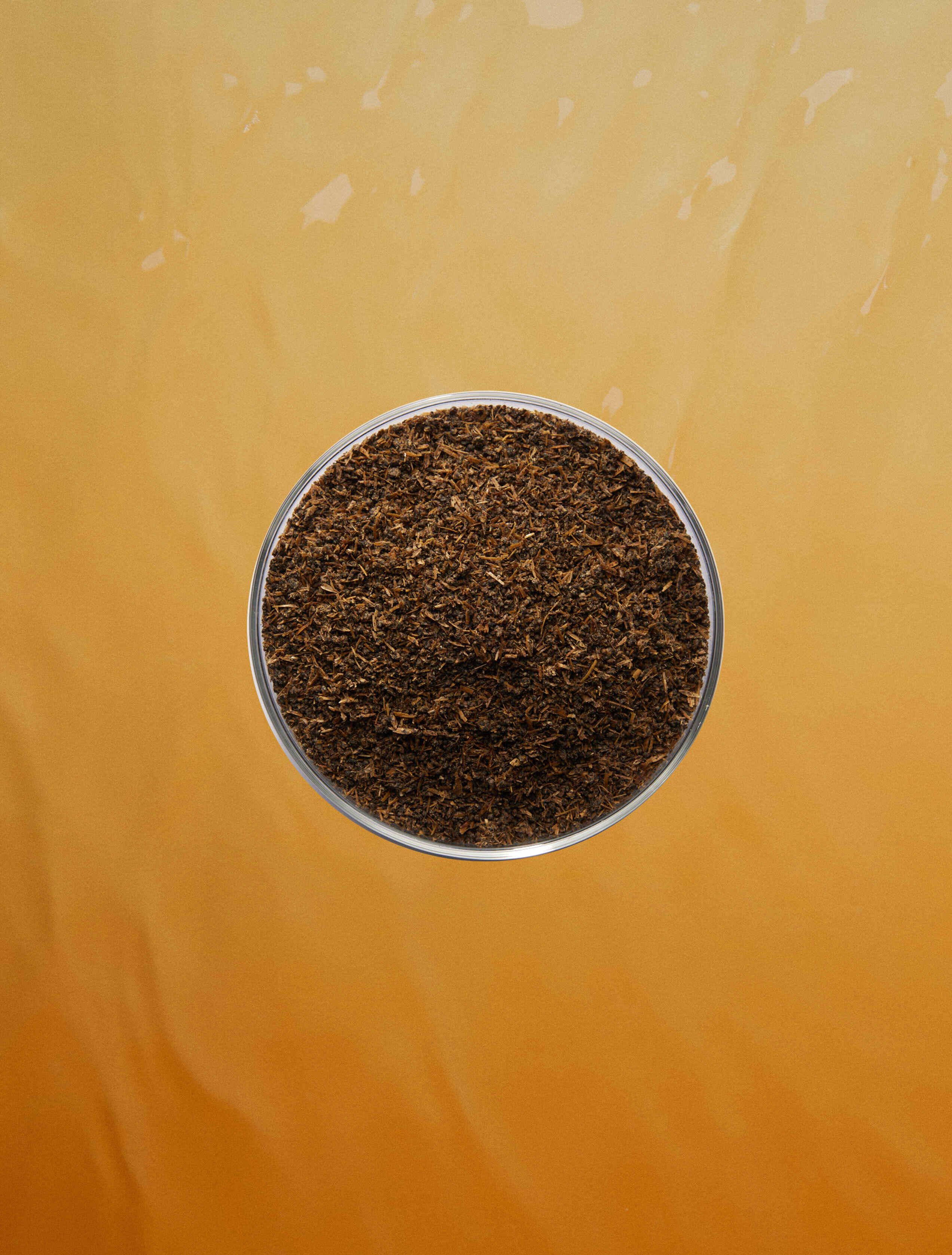 Fertilizer in a petri dish on an orange background