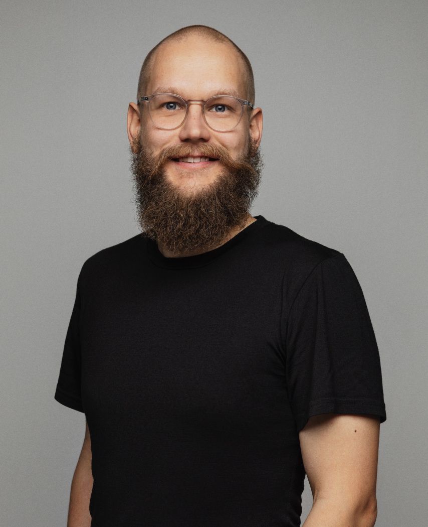 A bald smiling man with a beard in a black t-shirt