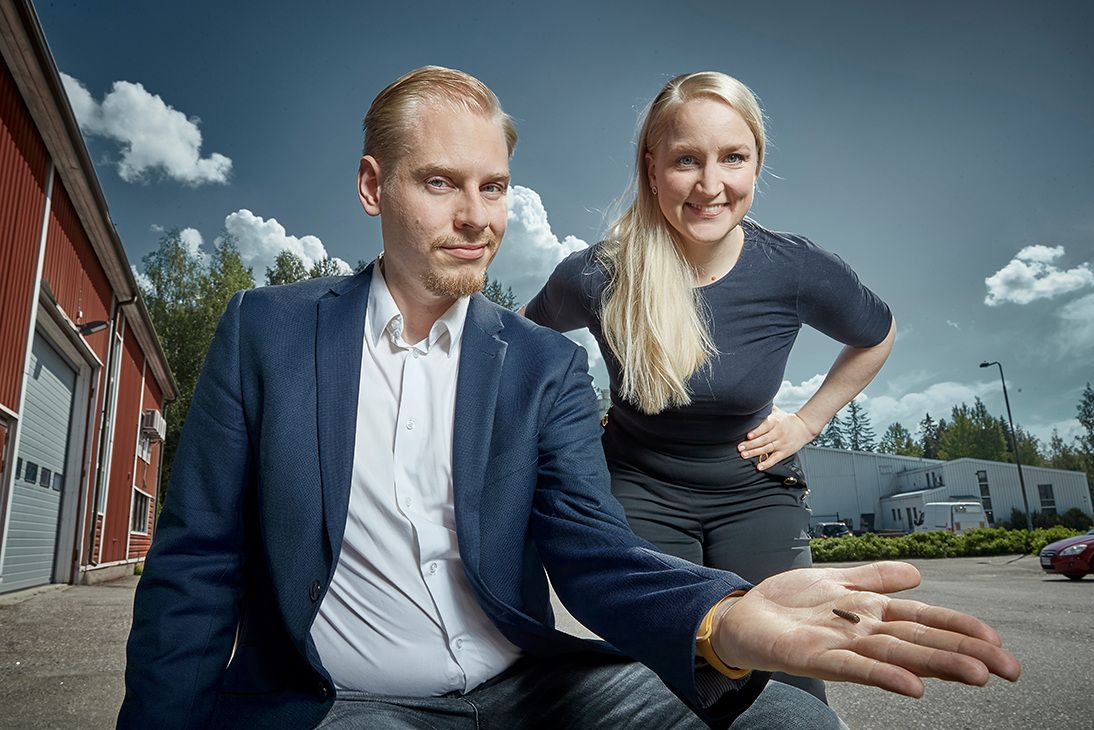Volare CEO Tuure Pariainen holds a fly larva on the palm of his hand while COO Jarna Hyvönen stands on the background
