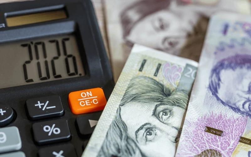 Czech koruna banknotes on a wooden desk next to a calculator