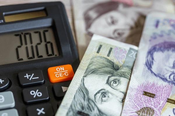 Czech koruna banknotes on a wooden desk next to a calculator