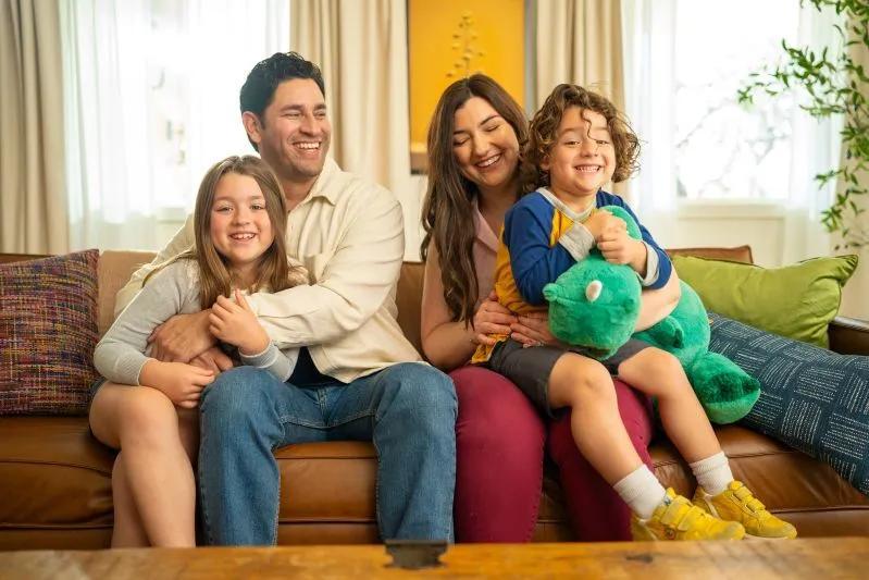 How Do Electrostatic Air Filters Work - image of a happy family sitting on a couch, smiling and spending quality time together in a cozy living room.